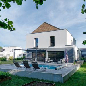 Construction à toiture audacieuse - façade arrière, piscine, jardin et terrasse